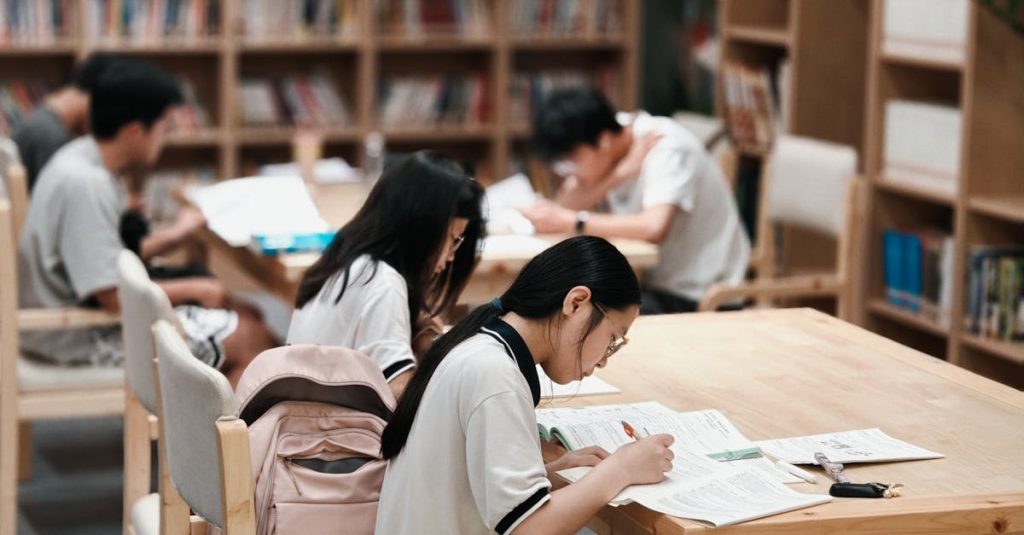 Group of students focused on studying inside a library, surrounded by bookshelves.